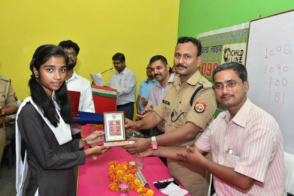 A young woman being honoured with a plaque by police and district officials